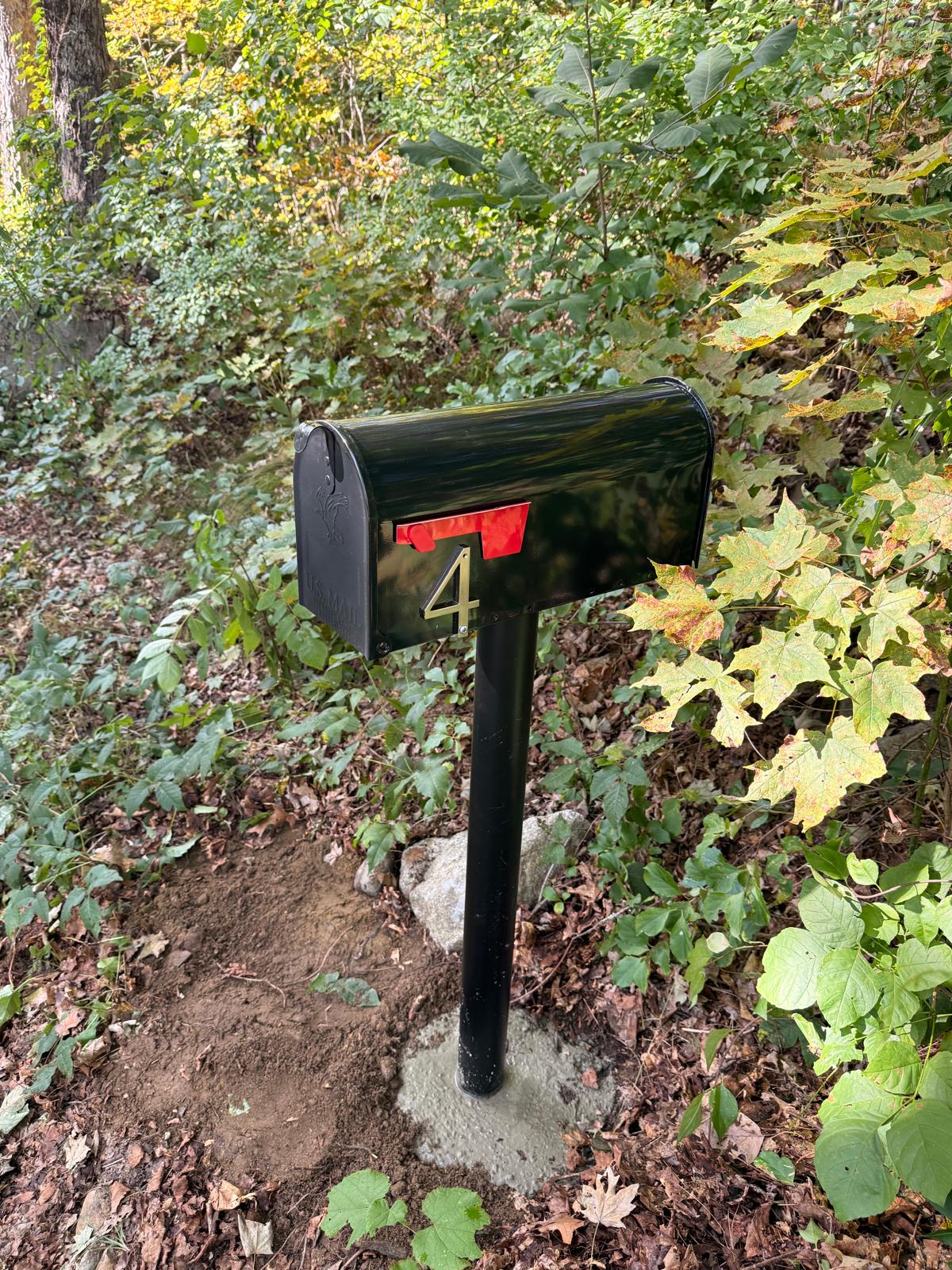 New black mailbox installed beside a residential yard