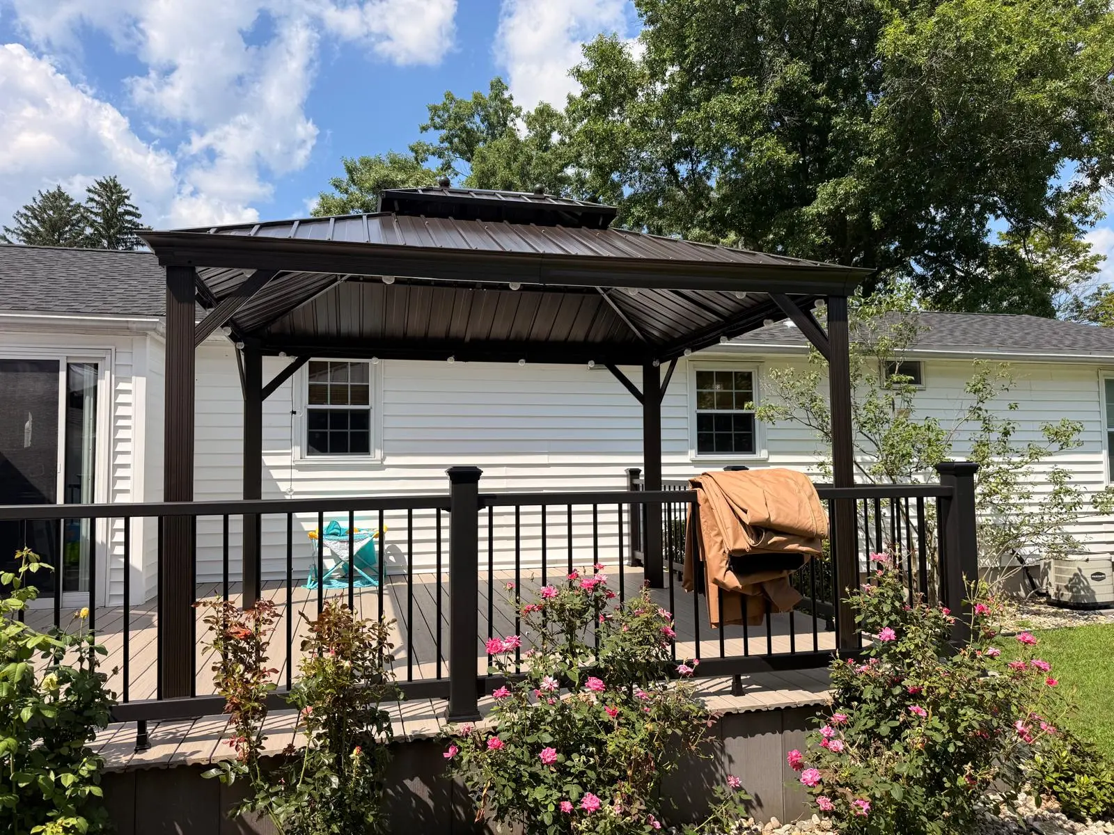 Black metal pergola installed in a landscaped yard
